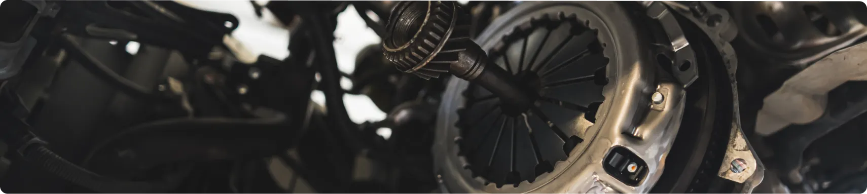 Transmission Repair & Replacement In Louisville, KY At Barnes Auto Service. Close-up view of a car’s clutch assembly and transmission components, showing detailed metal parts and mechanical connections inside an engine bay.