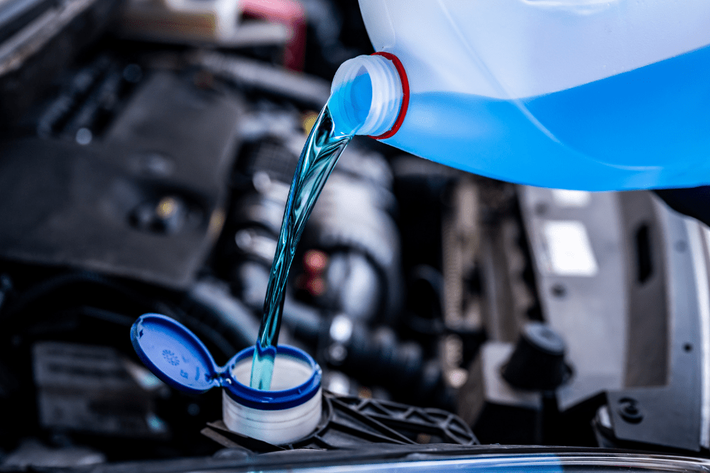 Cooling system service, auto repair in Louisville, KY by Barnes Auto Service. Image of blue coolant being poured into a vehicle’s reservoir, highlighting the importance of proper maintenance to protect engine performance and prevent overheating.