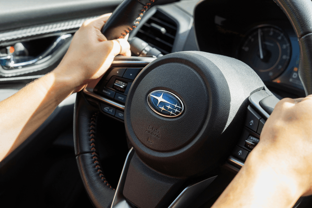 Subaru maintenance, auto repair Louisville, KY at Barnes Auto Service. Image of a driver holding the steering wheel of a Subaru.